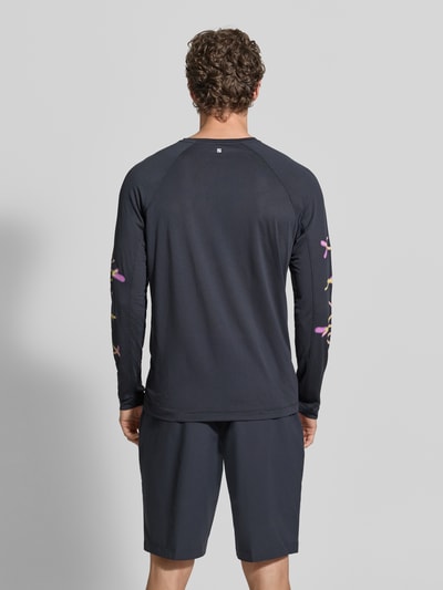 Männermodel trägt dunkles Funktionsshirt mit Logo Modell 'Kout' von Salomon, Regular Fit, Longsleeve, Rückansicht, Ganzkörperansicht Rückansicht.