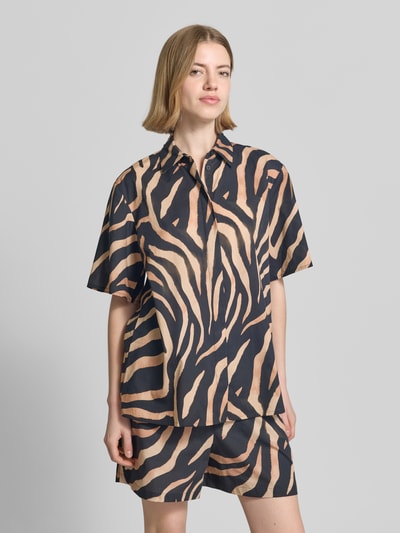 Frauenmodel trägt Regular Fit Hemdbluse aus reiner Baumwolle Modell 'CAMULE-1' von HUGO mit Optik:Allover-Muster, Animal-Print, Logo-Applikation aus Metall, verdeckter Knopfleiste, Kurzarm; meist in Beige und Schwarz mit fließender Struktur, Ganzkörperansicht von vorne.