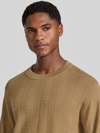 Męski model nosi sweter z bawełny Regular Fit Pullover aus reiner Baumwolle model 'Simoh' od HUGO, beżowy, faktura dzianiny, zbliżenie na górę ciała.