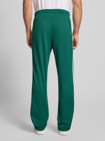 Männermodel trägt groene Sweatpants mit elastischem Bund von adidas Originals, locker fit, labelstiksel, steekzakken, rugaanzicht.