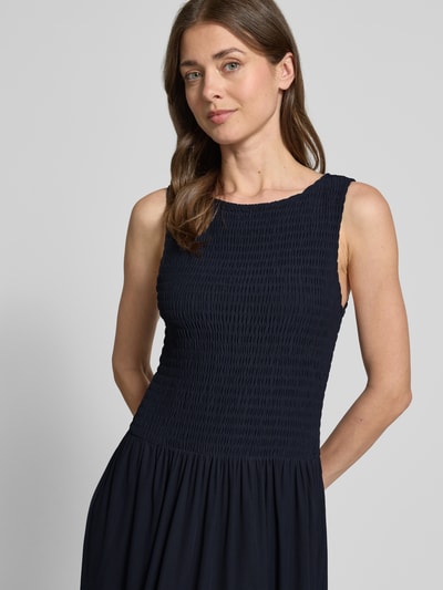 Frauenmodel trägt Midikleid aus Mesh mit Smok-Details von Christian Berg Woman Selection in Dunkelblau, gerader Schnitt, Nahaufnahme Oberkörper.