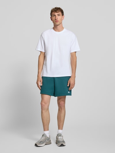 Männermodel trägt Relaxed Fit Shorts mit Logo-Stitching von New Balance, mieszanka bawełny, szorty, elastyczny pas z tunelem, szerokość w rozmiarze M: 42 cm, długość wewnętrzna nogawki: 18 cm, Ganzkörperansicht von vorne