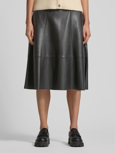 Frauenmodel trägt schwarzen Damen Midirock in Leder-Optik Modell 'BECKIE' von Soyaconcept mit Teilungsnähten, A-Linie, Ganzkörperansicht von vorne. Bundweite bei Größe 36: 40 cm, Gesamtlänge: 70 cm.