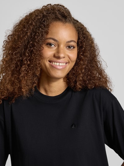 Frauenmodel trägt Regular Fit T-Shirt aus reiner Baumwolle Modell 'CHESTER' von Carhartt Work In Progress, schwarze Farbe, Nahaufnahme Oberkörper. Damen T-Shirt, Stehkragen, Halbarm, Rückenlänge bei Größe S: 56 cm.