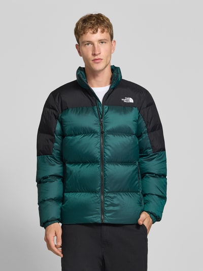 Männermodel trägt Regular Fit Jacke mit Daunen-Feder-Füllung Modell 'Diabolo' von The North Face in Stepp-Optik, grün und schwarz, Ganzkörperansicht von vorne. Rückenlänge bei Größe M: 70 cm, Schulterbreite: 47 cm, Brustweite: 58 cm, Ärmellänge: 69 cm, Logo-Stitching sichtbar.