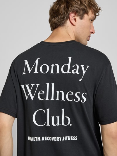 Męski model trägt Relaxed Fit T-Shirt aus reiner Baumwolle Modell 'CAP' von ONLY, czarne z białym nadrukiem, Ganzkörperansicht Rückansicht. Męski t-shirt von ONLY & SONS.