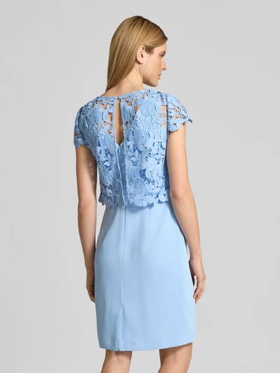 Frauenmodel trägt Knielanges Cocktailkleid im 2-in-1-Look von Christian Berg Cocktail in Hellblau mit Spitze, Gerader-Schnitt, Rückansicht. Rückenlänge bei Größe 36: 93 cm, Brustweite: 40 cm, Rundhalsausschnitt, Damen Cocktailkleid.