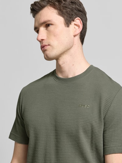 Männermodel trägt Regular Fit T-Shirt aus Baumwoll-Mix Modell 'AUSTIN' von HUGO in Optik: Unifarben mit Waffelstruktur, Nahaufnahme Oberkörper.