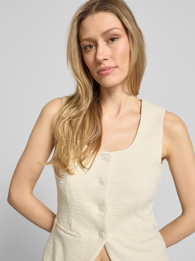 Vrouwenmodel draagt bodywarmer van viscosemix met structuurpatroon model 'KATE LUMINA' van ICHI, knoopsluiting, ronde hals, paspelzakken, slim fit, crèmekleurig, context: dames bodywarmer met stretch, ruglengte maat S 51 cm, schouderbreedte 33 cm, borstwijdte 39 cm. Nahaufnahme bovenlichaam.