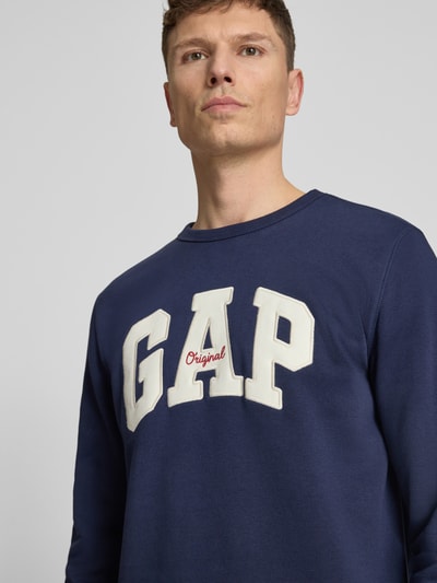 Männermodel trägt Sweatshirt mit Logo und Rundhalsausschnitt von GAP in Dunkelblau aus Baumwoll-Mix, Regular-Fit, Nahaufnahme Oberkörper.