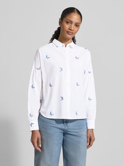 Modelka nosi Regular Fit Bluse mit Stitchings Modell 'LUCY' od 0039 Italy, biała bawełna, niebieskie hafty, widok całej sylwetki z przodu.