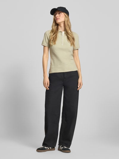Frauenmodel trägt Slim Fit Poloshirt mit Label-Stitching von Gant aus Baumwoll-Elasthan-Mix, Knopfleiste, Rückenlänge 59 cm, Ganzkörperansicht von vorne.