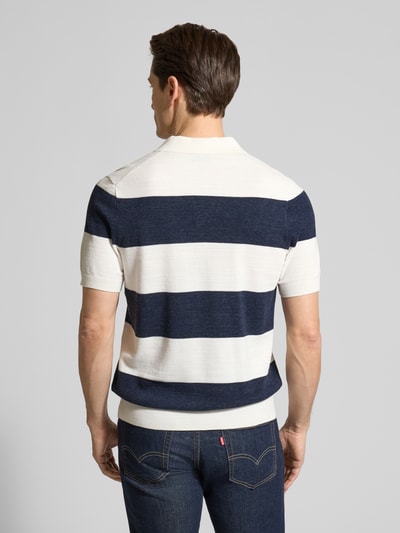 Męski model ma na sobie Slim Fit Poloshirt aus Baumwoll-Mix in Strick-Optik od OLYMP Level Five, krój slim fit, paski granatowo-białe, krótki rękaw, elastyczne wykończenia, bawełniany miks, widok całej sylwetki z tyłu.