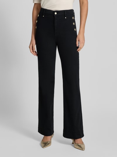Frauenmodel trägt High Waist Palazzo Jeans mit seitlichen Knöpfen von GUESS, schwarz, Baumwoll-Mix, Nahaufnahme Oberkörper bis Füße, Modell 'NEW FAYE', Stretch-Anteil.