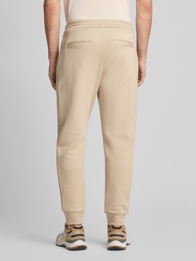 Männermodel trägt Regular Fit Sweatpants aus reiner Baumwolle von ARMANI EXCHANGE in Beige mit Gesäßtaschen, elastischen Abschlüssen, Label-Print, Ganzkörperansicht Rückansicht.