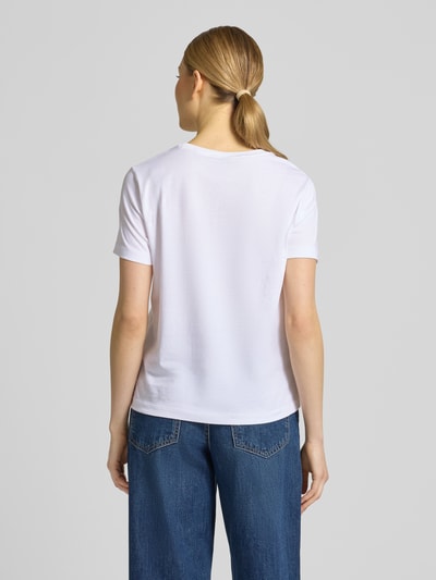 Frauenmodel trägt T-Shirt mit Label-Print und Rundhalsausschnitt von Gant aus reiner Baumwolle im Regular-Fit, Rückenlänge 57 cm, Ganzkörperansicht Rückansicht.