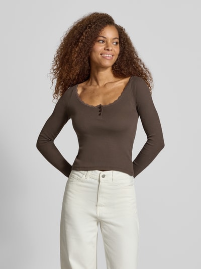 Vrouwenmodel draagt shirt met lange mouwen in bruin met riblook, met kant, knoopsluiting en slim fit, Model 'MAYA' van NOISY MAY®, gemaakt van mix van katoen en elastaan, ruglengte bij maat S 51 cm, close-up bovenlijf vooraanzicht.