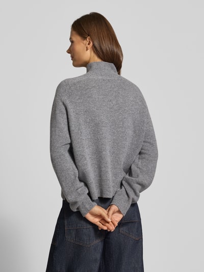 Frauenmodel trägt Strickpullover mit Stehkragen Modell 'LYZIMA' von DRYKORN, reine Baumwolle, grau meliert, Rückenansicht, Ganzkörperansicht von hinten.