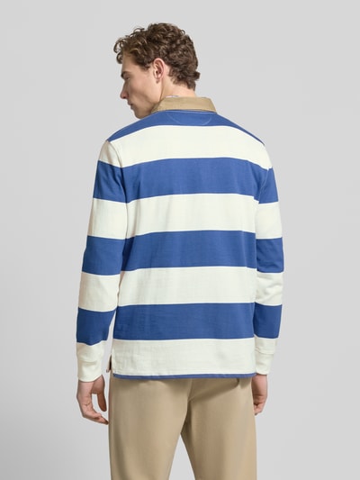 Męski model nosi bluzę Sweatshirt mit Label-Stitching od Polo Ralph Lauren z bawełny, krój regular fit, kołnierzyk polo, długie rękawy, niebiesko-białe szerokie pasy, prążkowane zakończenia rękawów, wyhaftowane logo; widok całej sylwetki od tyłu.