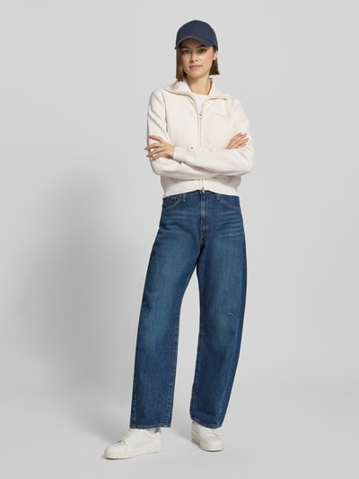 Frauenmodel trägt Slim Fit Strickjacke mit aufgesetzten Taschen von Tommy Jeans, Optik: Unifarben, Strickoptik, Ganzkörperansicht von vorne.