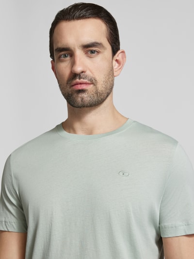 Męski model nosi Regular Fit T-Shirt aus reiner Baumwolle von Tom Tailor, jednolity kolor, logo, krój regular fit, okrągły dekolt, krótki rękaw, bawełna, zbliżenie górnej części ciała.