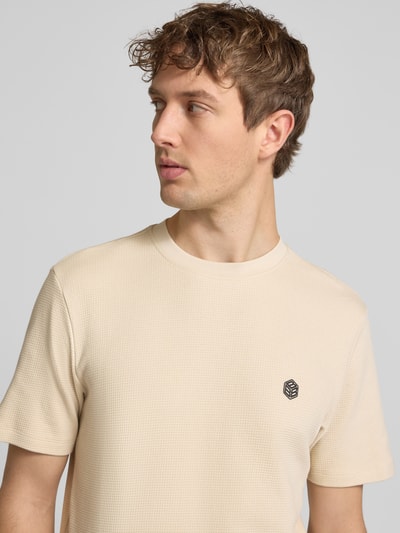 Männermodel trägt T-Shirt mit Label-Detail Modell 'FILLIP' von Blend in Beige, Reine Baumwolle, Gerader-Schnitt, Nahaufnahme Oberkörper.