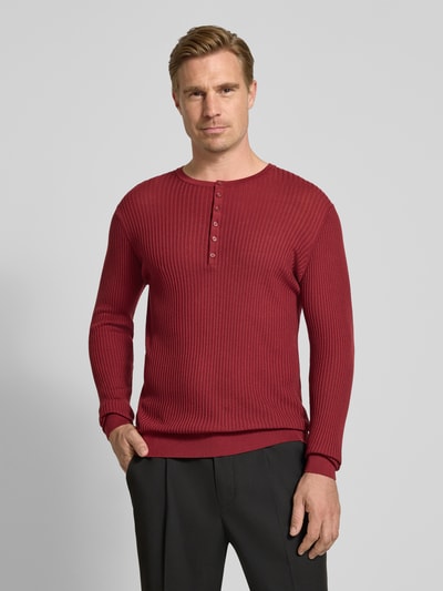 Männermodel trägt Strickpullover aus Lyocell-Woll-Mix mit Knopfleiste von Antony Morato in Rot, Ripp-Optik, Nahaufnahme Oberkörper, Slim Fit.