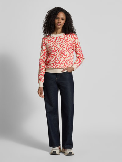 Frauenmodel trägt Slim Fit Pullover aus Viskose-Mix Modell 'JACQUARD' von Vila, rot-weißes Animal-Stitching, Strick-Optik, Ganzkörperansicht von vorne.