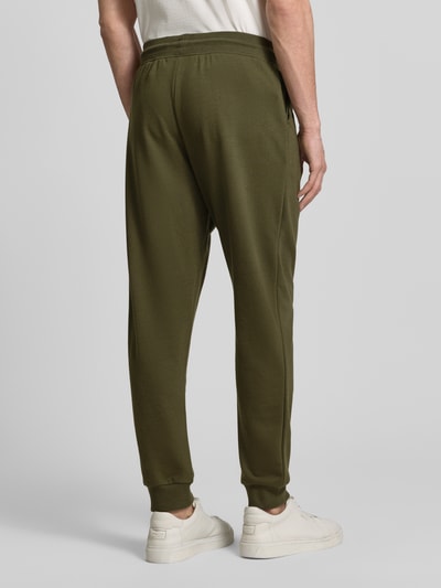 Männermodel trägt Comfort Fit Sweatpants aus katoenmix van Tommy Hilfiger, uni, label stitching, geribde boorden, zijzakken, ganzkörperansicht rückansicht.