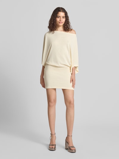 Frauenmodel trägt Minikleid mit U-Boot-Ausschnitt von Gina Tricot in hellem Beige, figurbetont, Material-Mix mit Stretch, Ganzkörperansicht von vorne.