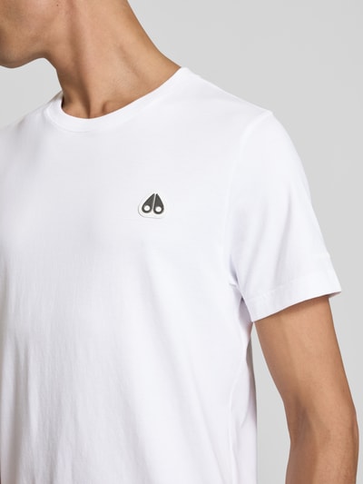 Männermodel trägt weißes Regular Fit T-Shirt mit Logo-Detail von Moose Knuckles aus Baumwolle, Rundhalsausschnitt, Nahaufnahme Oberkörper.