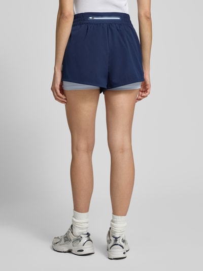 Frauenmodel trägt Regular Fit Sport-Shorts mit Logo-Applikation von Lacoste Sport, unifarben blau, elastischer Bund, Rückansicht Ganzkörperansicht.
