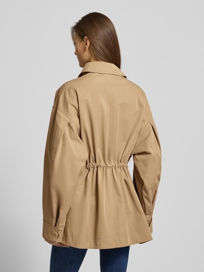 Modelka kobieca nosi beżową Jacke mit Stehkragen und Pattentaschen von Jake*s Casual, bawełniany miks, taliowany krój, widok całej sylwetki od tyłu.