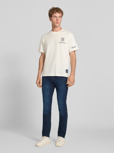 Männermodel trägt Slim Fit Jeans aus Baumwoll-Mix Modell 'LOOM' von ONLY in Dunkelblau, kombiniert mit weißem Shirt, Ganzkörperansicht von vorne, Herren Slim Fit Jeans von ONLY & SONS.