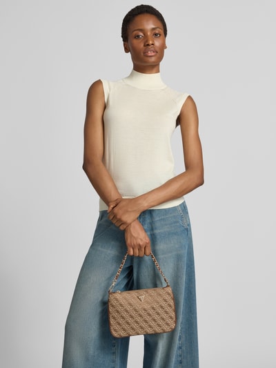 Frauenmodel trägt Shoulder Bag mit Allover-Brand-Stickereien von GUESS, beige, strukturierte Textur, Label-Applikation, Ganzkörperansicht von vorne. Schulterriemen abnehmbar, Hauptfach mit Reißverschluss, Maße 25x17x1 cm, Riemenlänge 42 cm.
