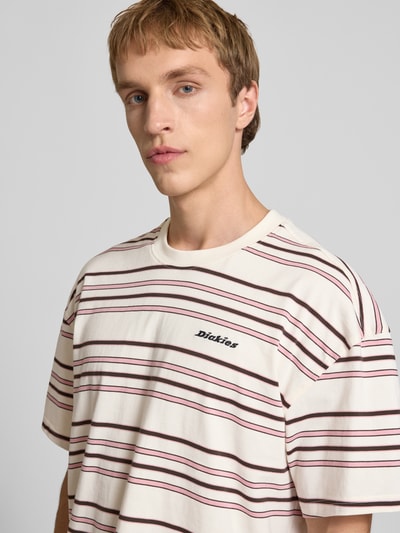 Mannenmodel draagt T-shirt met logo-stitching model 'EAST LIBERTY' van Dickies van zuivere katoen in relaxed fit met ronde hals, roomwit met rood gestreept patroon, detailopname bovenlichaam.