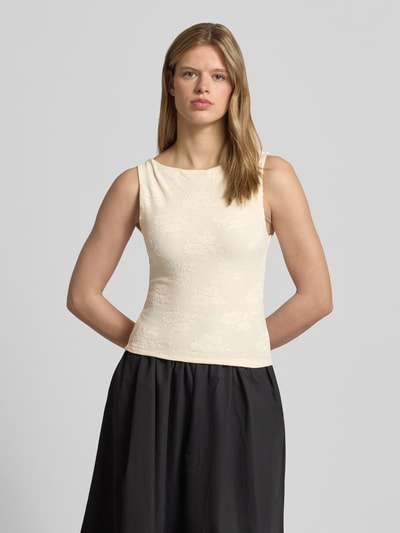 Modelka kobieca nosi Slim Fit Top mit floralem Allover-Stitching Modell 'Jacquard' od Gina Tricot, elastyczna mieszanka materiałów, krój slim fit, długość tyłu w rozmiarze S: 47 cm, jasny beż z delikatnym kwiatowym haftem, gładka tekstura, widok całej sylwetki z przodu.