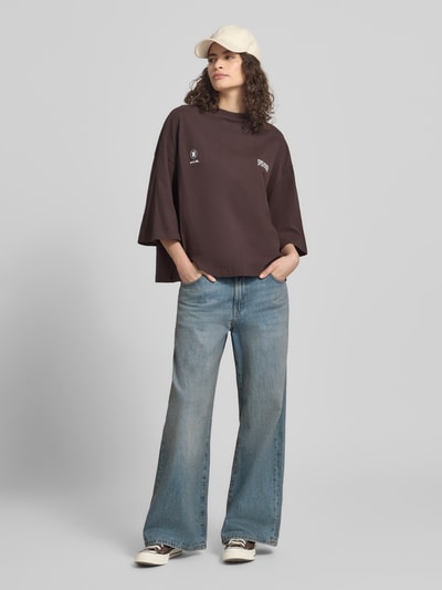 Kobiece model nosi Oversized T-Shirt mit Rundhalsausschnitt od Karo Kauer z bawełny, nadruk z logo, krój oversized, okrągły dekolt, długość tyłu 59 cm w rozmiarze S, całkowity widok z przodu.