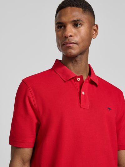 Männermodel trägt Regular Fit Poloshirt mit Logo-Stitching von Fynch-Hatton in Rot, reine Baumwolle, Nahaufnahme Oberkörper.