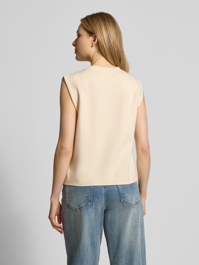 Frauenmodel trägt Regular Fit Strickjacke aus Viskose-Mix Modell 'GOLD' von Vero Moda in Beige, unifarben, Strickoptik, Ganzkörperansicht Rückansicht.