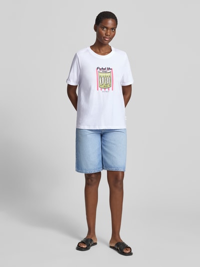 Frauenmodel trägt Regular Fit T-Shirt aus reiner Baumwolle von s.Oliver RED LABEL in Weiß mit farbigem Print, kombiniert mit Jeansshorts, Ganzkörperansicht von vorne. Damen T-Shirt