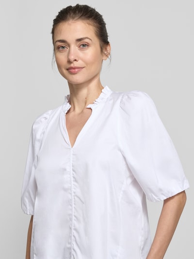 Kobiece model prezentuje Regular Fit Bluse mit V-Ausschnitt von Rich & Royal z bawełny, krój regular fit, dekolt w serek, rękaw o dł. 1/2, długość tyłu 54 cm, długość rękawów 36 cm; jasna tekstura, prosta forma, detaliczny widok na górną część ciała, ujęcie z przodu.