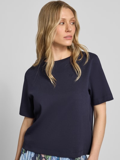 Modelka kobieca nosi T-Shirt mit Logo-Stitching Modell 'SVEHA' od Oui, granatowa bawełna, krój prosty, okrągły dekolt, długość tyłu 55 cm w rozmiarze 36, ujęcie górnej części ciała z przodu.