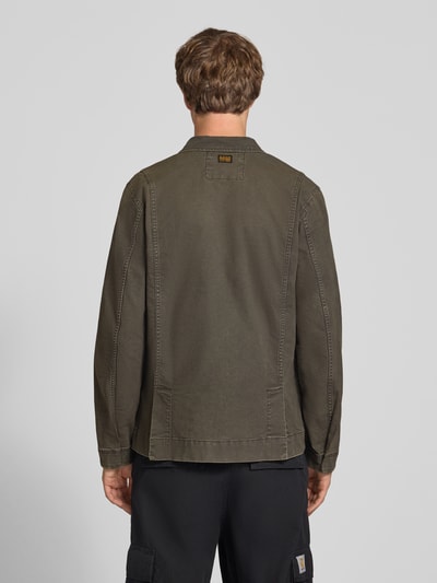 Männermodel trägt Slim Fit Jeansjacke aus reiner Baumwolle von G-Star RAW in Olivgrün mit sichtbaren Nähten, Ganzkörperansicht Rückansicht.