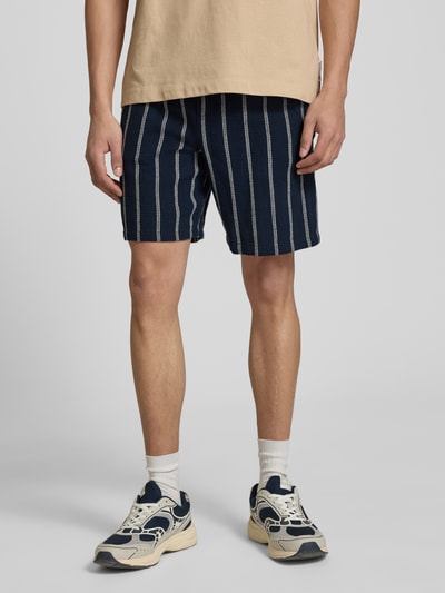 Männermodel trägt Regular Fit Shorts mit Tunnelzug von Jack & Jones aus reiner Baumwolle, dunkelblau mit weißen Streifen, Ganzkörperansicht von vorne.