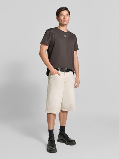 Männermodel trägt Regular Fit T-Shirt aus reiner Baumwolle von Diesel, dunkle Farbe, dezentes Logo-Detail, Ganzkörperansicht von vorne.