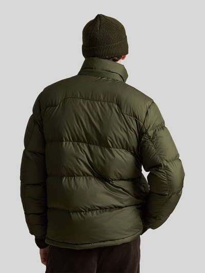 Männermodel trägt Regular Fit Daunenjacke mit Logo-Stitching von Polo Ralph Lauren in Olivgrün, glatte Oberfläche, Ganzkörperansicht Rückansicht. Herren Daunenjacke von Polo Ralph Lauren.