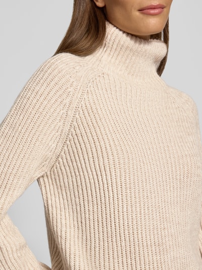 Frauenmodel trägt Strickpullover mit Stehkragen Modell 'ARWEN' von DRYKORN, Grobstrick aus Baumwoll-Mix in Beige, Nahaufnahme Oberkörper.