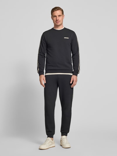 Männermodel trägt Sweatshirt mit Label-Details und Rundhalsausschnitt von EA7 Emporio Armani, dunkel, Baumwoll-Mix, Regular-Fit, Ganzkörperansicht von vorne, Rückenlänge bei Größe M: 63 cm, Ärmellänge bei Größe M: 66 cm.