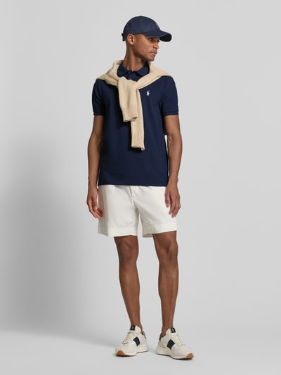 Männermodel trägt Slim Fit Poloshirt aus Baumwoll-Mix von Polo Ralph Lauren, Optik: Unifarben, mit Logo-Detail, Ganzkörperansicht von vorne.